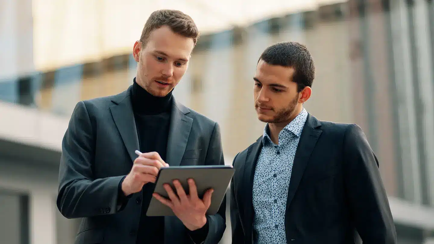 Zwei Männer prüfen Online-Marketing-Ergebnisse auf Smartphone.